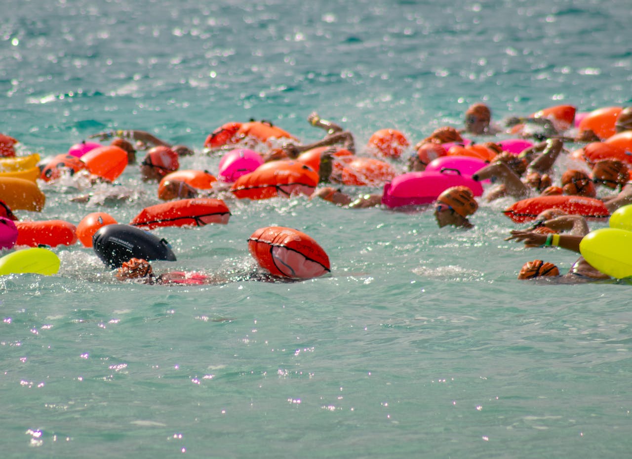 A dynamic group of swimmers with colorful lifebuoys in Bacalar Lagoon, Mexico, engaged in a summer swimming race.